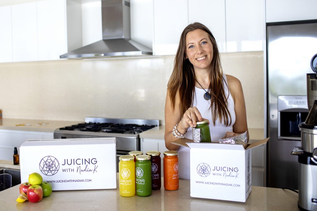 Nadia K packing a juice cleanse into a box at kitchen bench