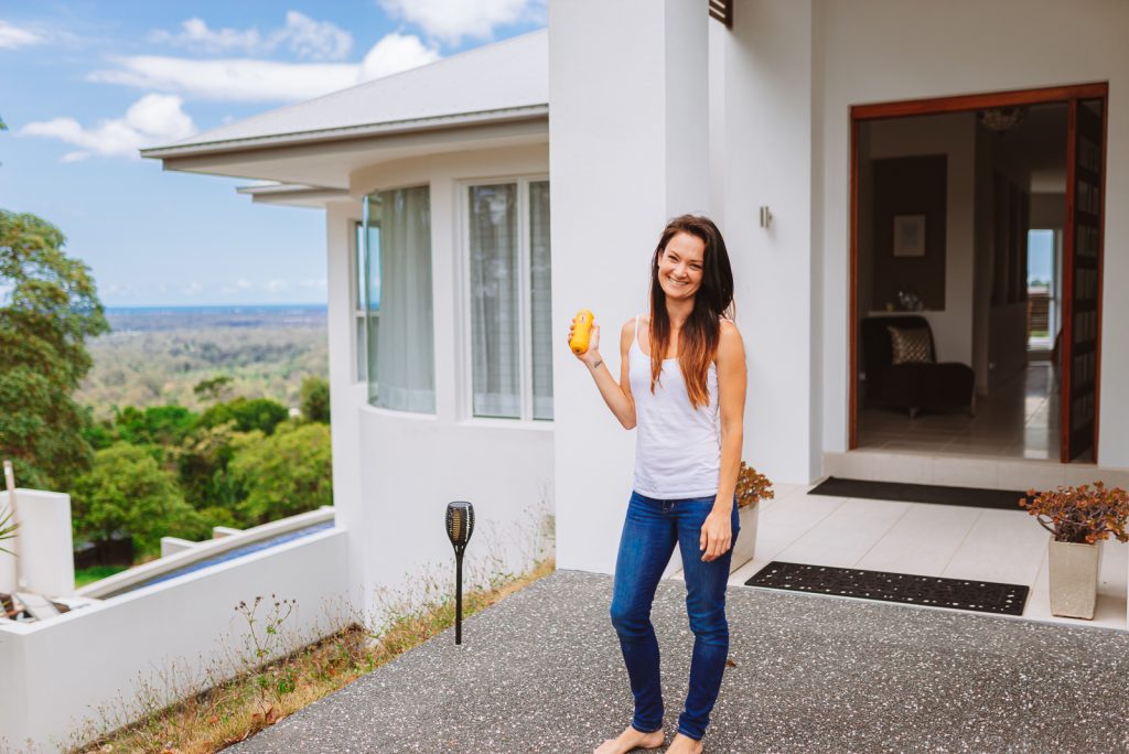 Lady holding Tesla's Home Water Kit in front of house