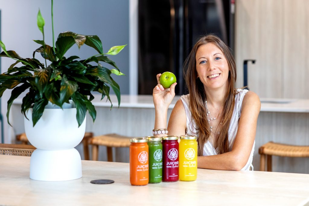 Nadia sitting at table with Tropical Juices in front of her and an apple in her hand